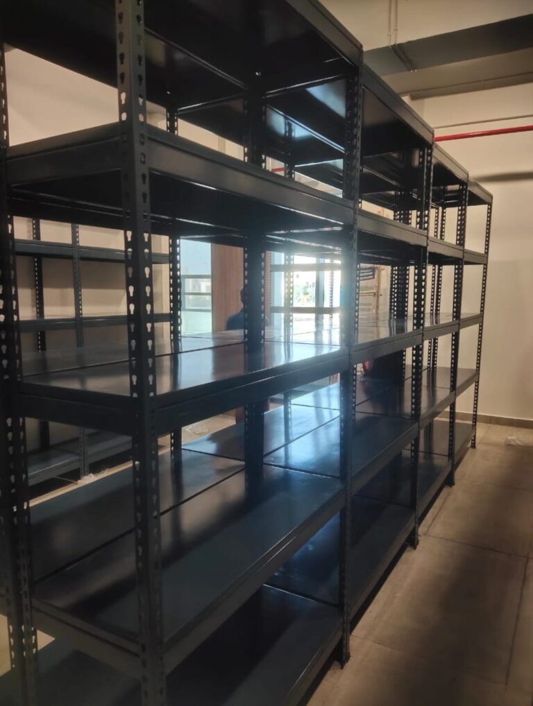 boltless rack of dark grey color installed at an office for storage purpose. 36 inches width, 15 inches depth, 5 shelves and 6feet height. wall is white in color.