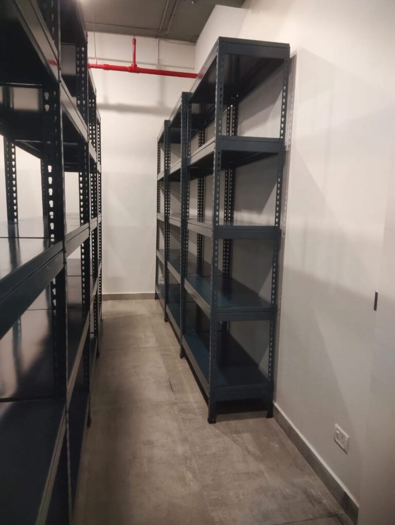 boltless racks of dark grey color installed at an office for storage purpose. 36 inches width, 15 inches depth, 5 shelves and 6feet height. wall is white in color.